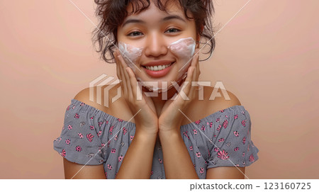 Young woman applying creamy face wash on cheeks 123160725