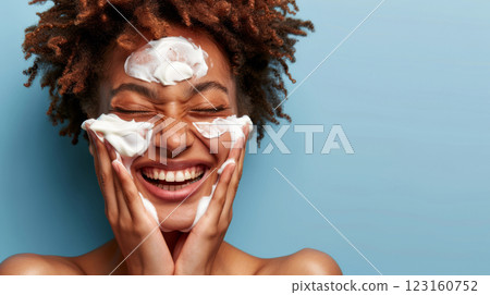 Joyful young woman applying facial cleanser with a beaming smile 123160752