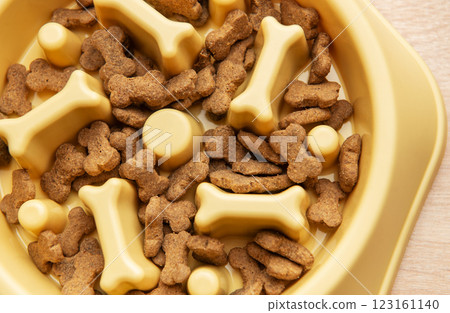 Dry dog food in bowl shaped like bones filling a slow feeder bowl Dry dog food in bowl shaped like bones filling a slow feeder bowl 123161140