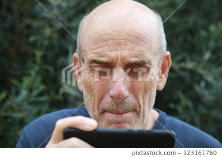Elderly Man Watches A Football Match On The Phone Disappointed At The Defeat Elderly Man Watches A Football Match On The Phone Disappointed At The Defeat 123161760