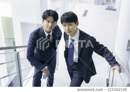 Portrait of two young businessmen standing on the stairs of an office building 123162140