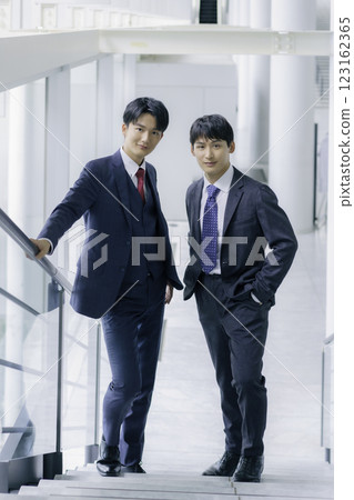Portrait of two young businessmen standing on the stairs of an office building, vertical position 123162365