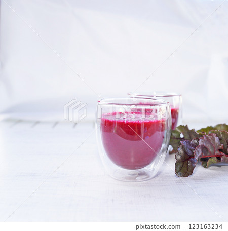 A cup of fresh beetroot juice with leaves on table. A cup of fresh beetroot juice with leaves on table. 123163234