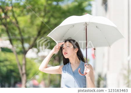 一位打著陽傘行走的女商人在辦公區看起來很性感 一位打著陽傘行走的女商人在辦公區看起來很性感 123163463