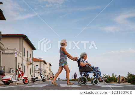 Daughter pushes her elderly mother in wheelchair Daughter pushes her elderly mother in wheelchair 123163768