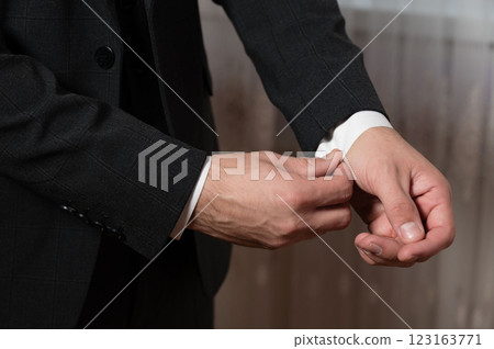 Man adjusting his cufflinks, preparing for a formal event.  Sharp details and elegant style. 123163771