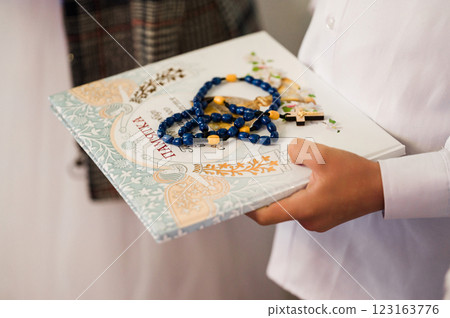 Child holding a religious book and rosary beads. A moment of faith and devotion. 123163776