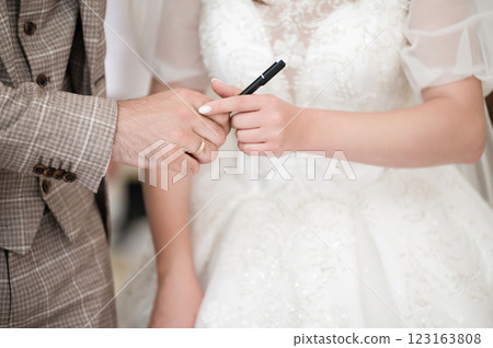 A bride and groom exchange a pen, a symbol of their commitment and the start of their journey together. 123163808