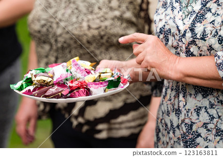 Woman offering a plate of assorted candies outdoors. Woman offering a plate of assorted candies outdoors. 123163811