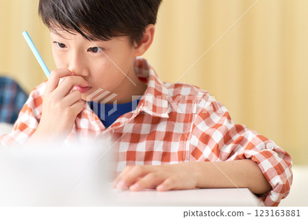 A male elementary school student studying while scratching the tip of his nose 123163881