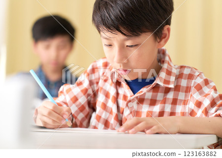 A male elementary school student writing with a serious expression 123163882