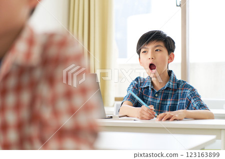 A male elementary school student yawning during class A male elementary school student yawning during class 123163899
