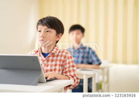 A male elementary school student taking a class with a serious expression A male elementary school student taking a class with a serious expression 123163916