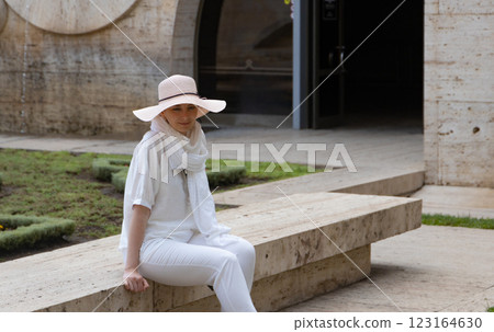 Relaxing in a serene courtyard, a woman in white enjoys a peaceful moment under the sun during midday summer Relaxing in a serene courtyard, a woman in white enjoys a peaceful moment under the sun during midday summer 123164630