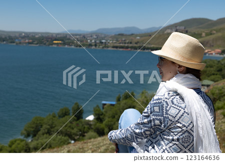 Enjoying a peaceful moment by the serene lake with mountains in the backdrop during a sunny day 123164636