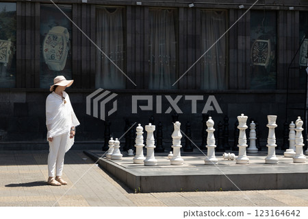 Elegant woman contemplating a giant chess game in a historic urban setting during a sunny afternoon 123164642
