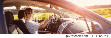 Young woman sitting behind the wheel and driving a car on a sunny day. Young woman sitting behind the wheel and driving a car on a sunny day. 123165041