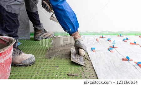 Tiler at work applies cement glue to the floor to install tiles. Construction. 123166614