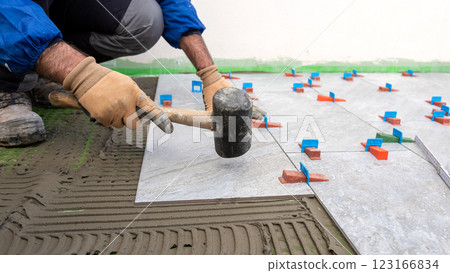 Tiler at work with rubber tile hammer. Construction. 123166834
