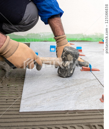 Tiler at work with rubber tile hammer. Construction. 123166838