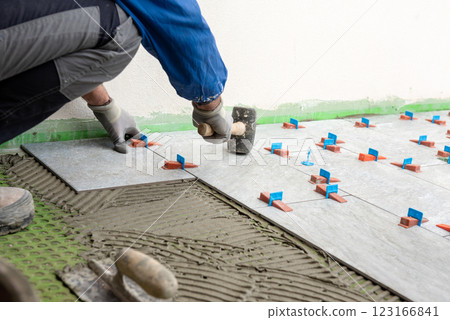 Tiler at work with rubber tile hammer. Construction. Tiler at work with rubber tile hammer. Construction. 123166841
