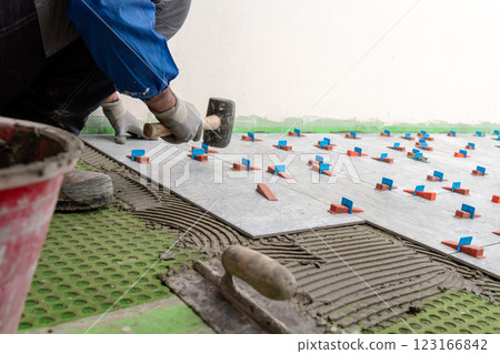 Tiler at work with rubber tile hammer. Construction. 123166842