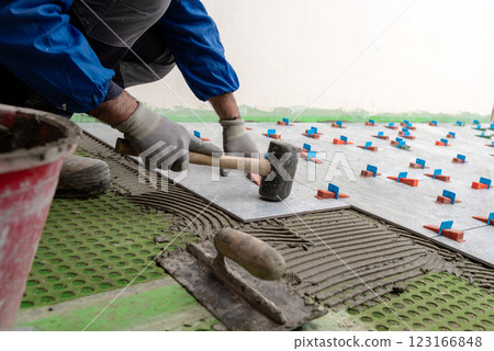 Tiler at work with rubber tile hammer. Construction. 123166848