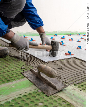 Tiler at work with rubber tile hammer. Construction. 123166849