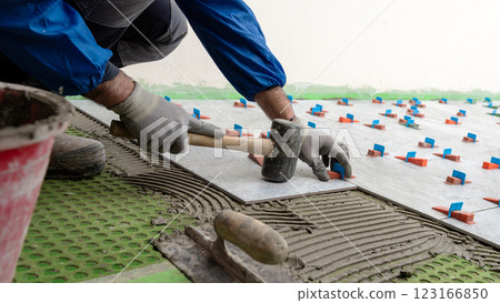 Tiler at work with rubber tile hammer. Construction. Tiler at work with rubber tile hammer. Construction. 123166850