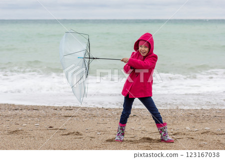 Child holding broken umbrella because of wind on sea shore Child holding broken umbrella because of wind on sea shore 123167038