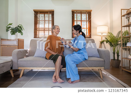 Young Nurse Providing Compassionate Health Care Advice to Elderly Woman in a Cozy Living Room Setting 123167345