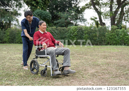 Nursing aide joyfully pushing elderly man in wheelchair through a garden, promoting mobility and care Nursing aide joyfully pushing elderly man in wheelchair through a garden, promoting mobility and care 123167355