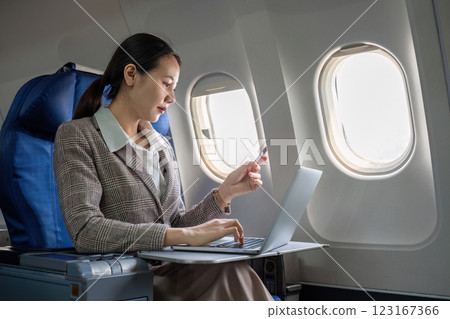 Young Asian woman holding credit card shopping online using website on laptop Sitting near window in first class on airplane during flight, travel and business concept. 123167366