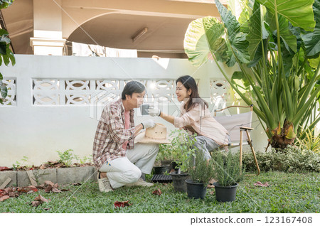 Diverse couple gardening together, sharing a joyful moment near potted plants. 123167408
