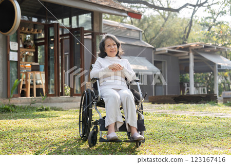 Elderly Woman Enjoying Outdoors in Wheelchair Near Modern House on a Sunny Day Elderly Woman Enjoying Outdoors in Wheelchair Near Modern House on a Sunny Day 123167416