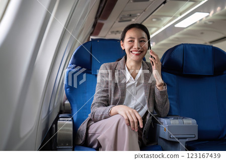 Young woman talking on the phone, communicating on business before traveling Sitting near window in first class on airplane during flight, travel and business concept. 123167439