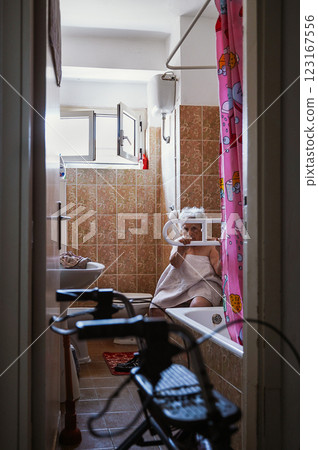 Elderly disabled woman sits in a bathroom 123167556