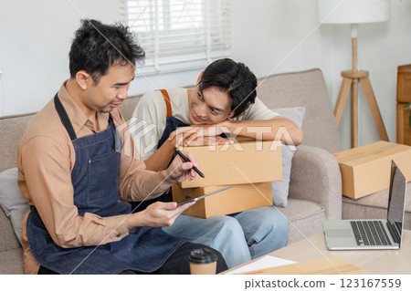 LGBT couple strategizing for online sales, sharing insights while surrounded by packing boxes at home 123167559