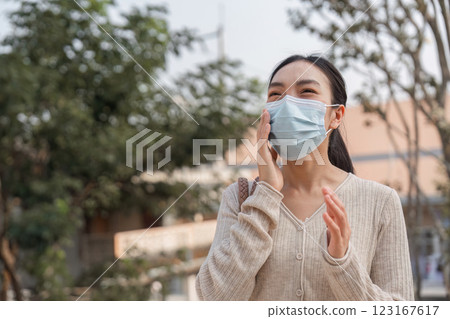 Young woman smiling while wearing a mask outdoors, addressing pollution concerns. Young woman smiling while wearing a mask outdoors, addressing pollution concerns. 123167617