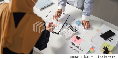 Diverse female finance professionals discussing financial reports in an office setting. 123167646