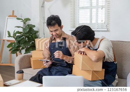 LGBT couple enthusiastically collaborating on their online sale strategies while packing orders 123167656