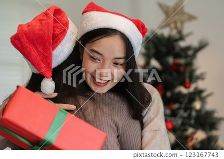 Joyful Young Couple Celebrating Christmas with Surprise Gift Exchange in Festive Holiday Setting Joyful Young Couple Celebrating Christmas with Surprise Gift Exchange in Festive Holiday Setting 123167743
