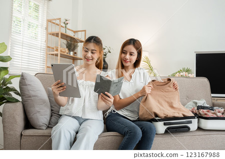 Two young female friends pack their suitcases and passports in preparation for the weekend. 123167988