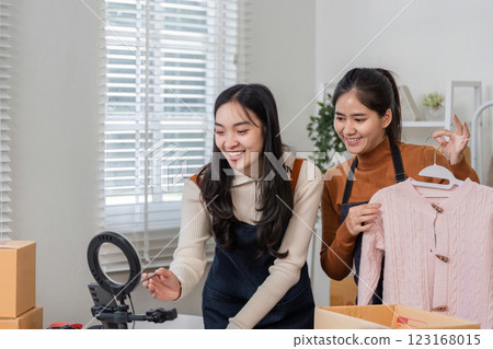 Couple selling clothes online joyfully preparing products in a bright home office 123168015