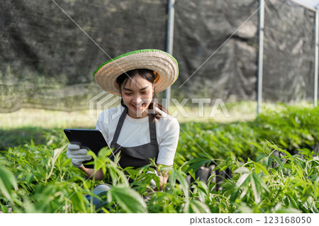 Young Woman Using Modern Technology in Agriculture for Sustainable Farming Practices and Crop Management 123168050