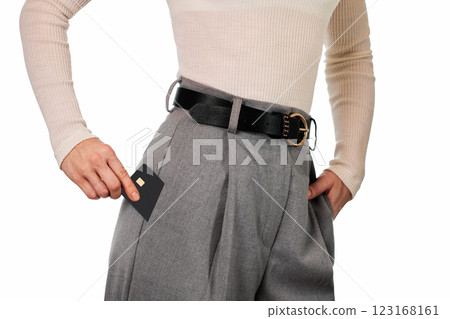 Caucasian female hand putting black premium credit bank card in grey pants pocket on white background. Money finance 123168161
