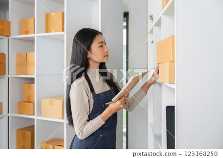 Young woman inspecting inventory and updating records in a modern storage area. 123168250