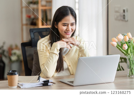 Freelance businesswoman working from home, engaging with clients on a laptop, showcasing productivity and focus. 123168275