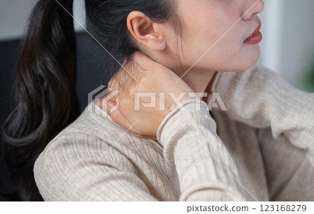 Close-up of a woman rubbing her neck to ease discomfort while seated at her desk. 123168279
