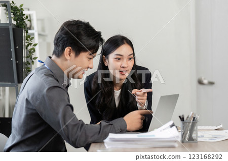 Diverse business partners collaborating on a laptop in a modern office. Diverse business partners collaborating on a laptop in a modern office. 123168292